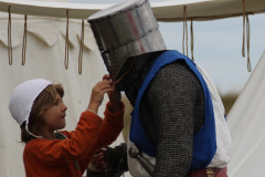 A young page helps his lord prepare for battle